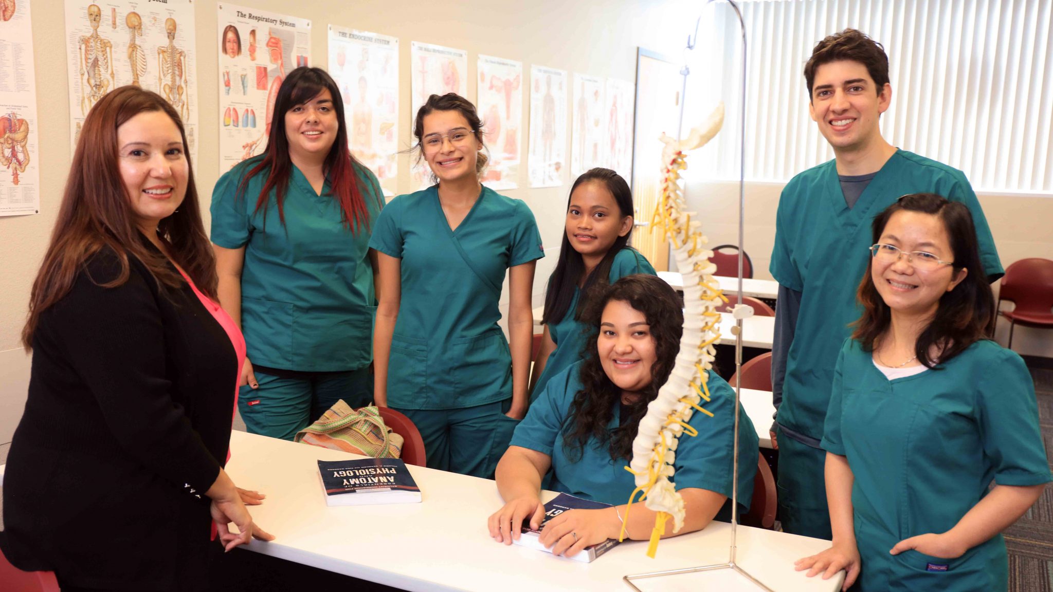 Five nursing students with an instructor in an anatomy classroom.